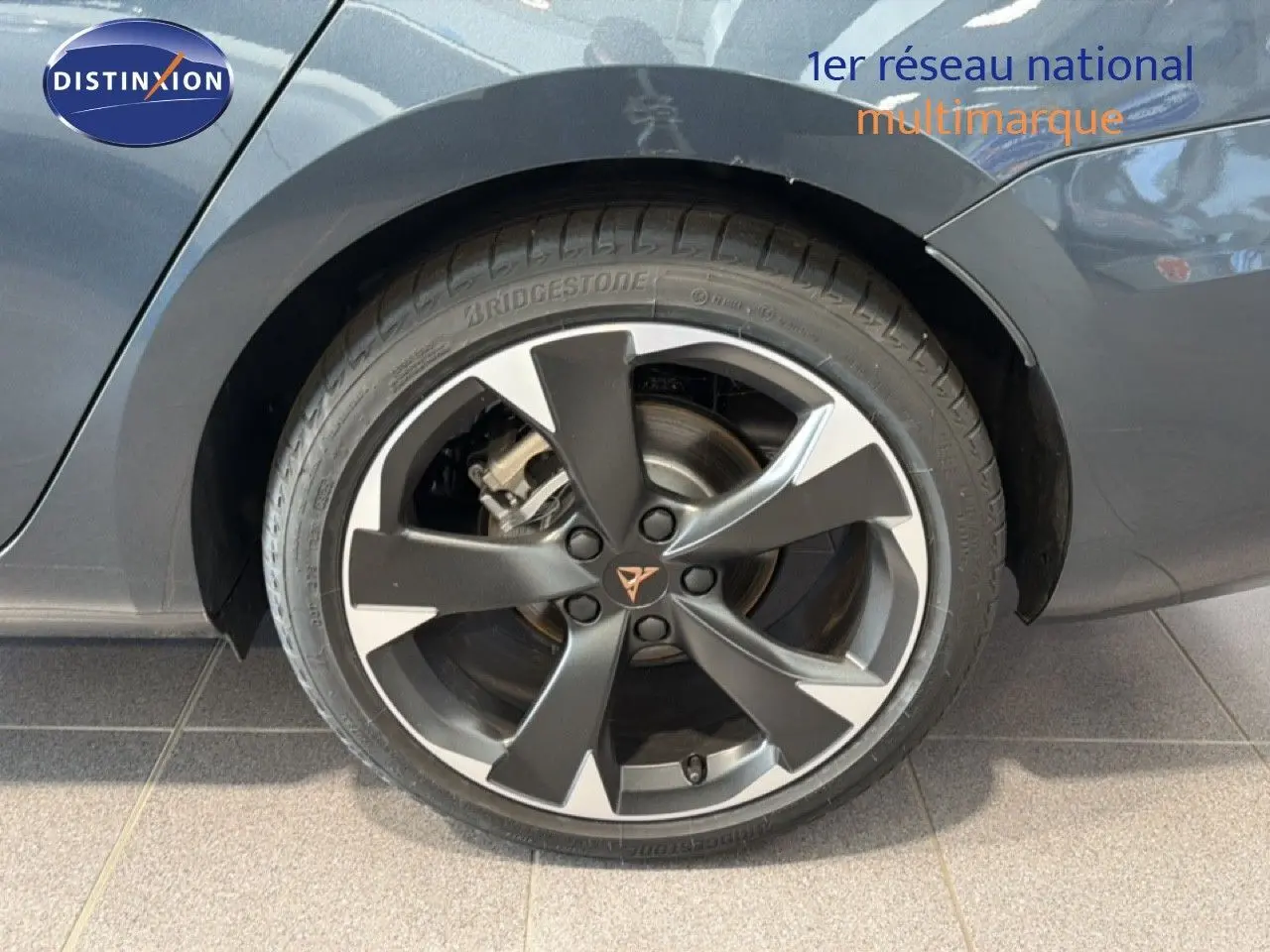 Gros plan sur la roue arrière droite d'une CUPRA LEON ST gris magnétique métal avec jante bi-ton et logo CUPRA central.