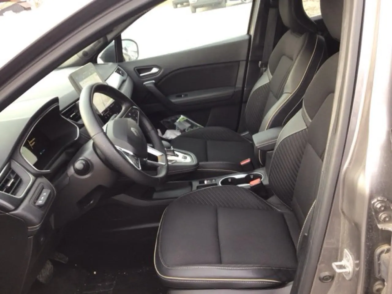 Vue intérieure côté conducteur du Renault SYMBIOZ 2025, sièges noirs avec surpiqûres claires et tableau de bord moderne.