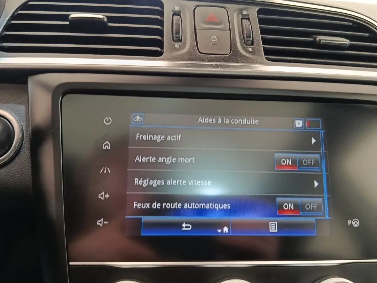 Écran tactile central du tableau de bord du Renault Kadjar blanc, affichant les aides à la conduite activées.