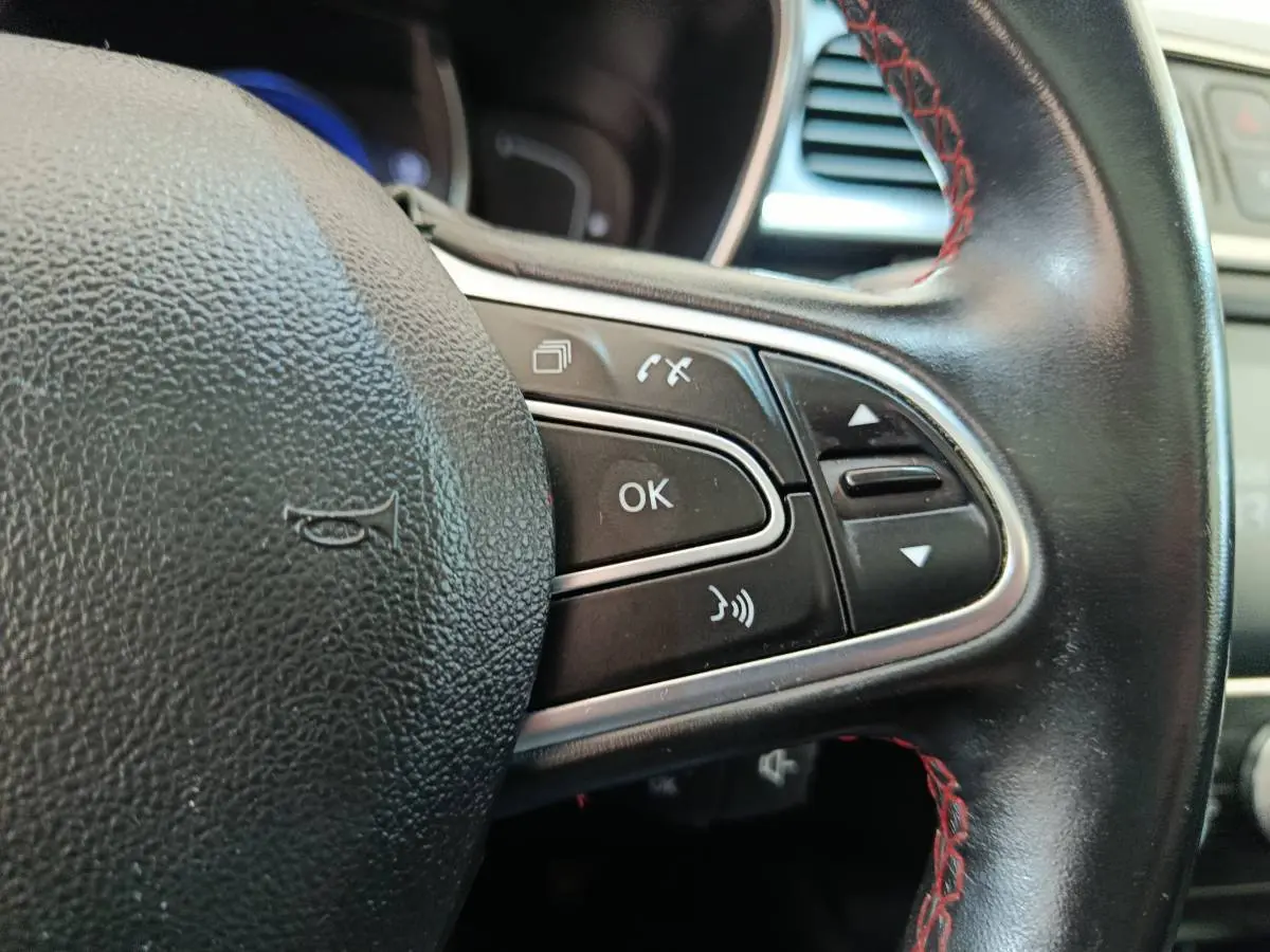Gros plan sur le volant cuir noir avec surpiqûres rouges du Renault Kadjar, boutons de commande multifonctions visibles.