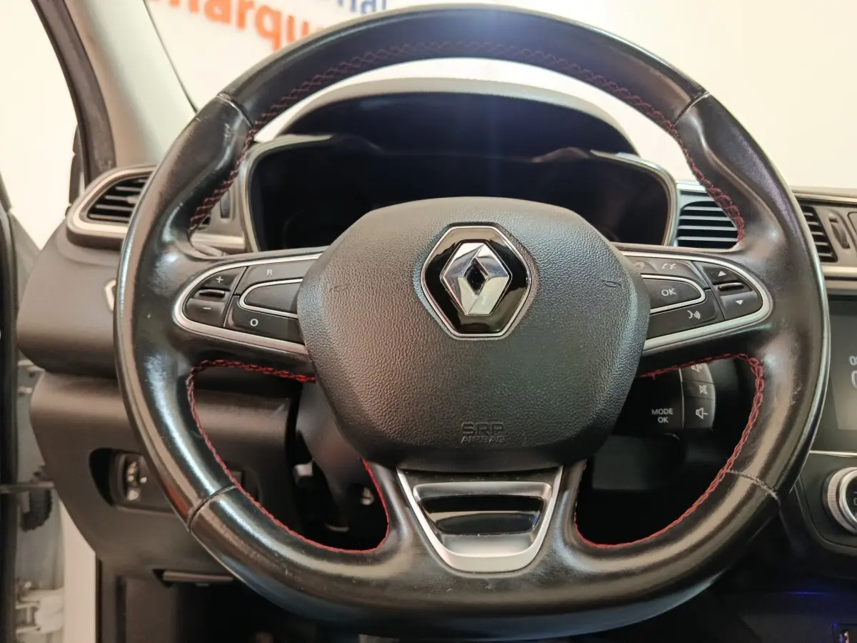 Gros plan sur le volant cuir noir avec surpiqûres rouges du Renault Kadjar Blanc, tableau de bord partiellement visible.