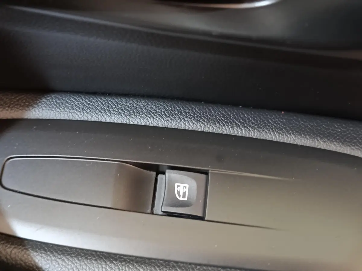 Gros plan sur le bouton de commande de la vitre électrique côté conducteur du Renault Kadjar blanc, version Black Edition.