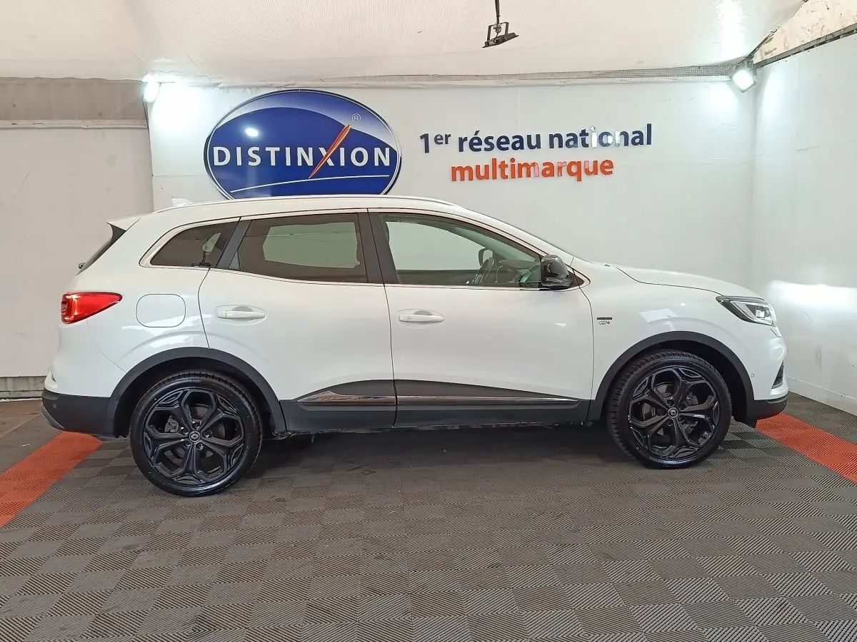 Profil droit d’un Renault Kadjar Blanc Black Edition 2020 avec jantes noires et détails chromés sous un éclairage intérieur.