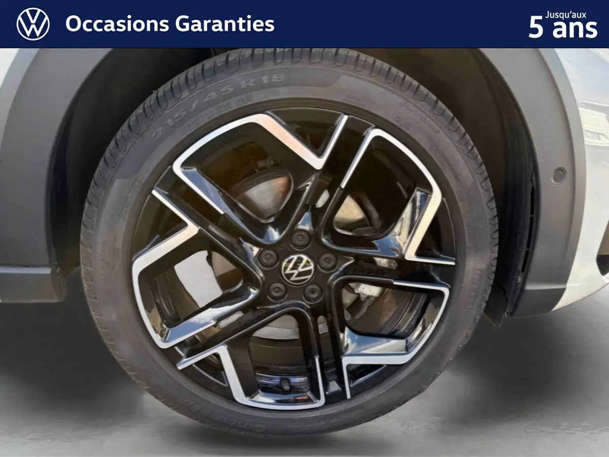Gros plan sur la jante alliage noire et argent 18 pouces du Volkswagen Taigo gris, avec pneu 215/45 R18 visible.