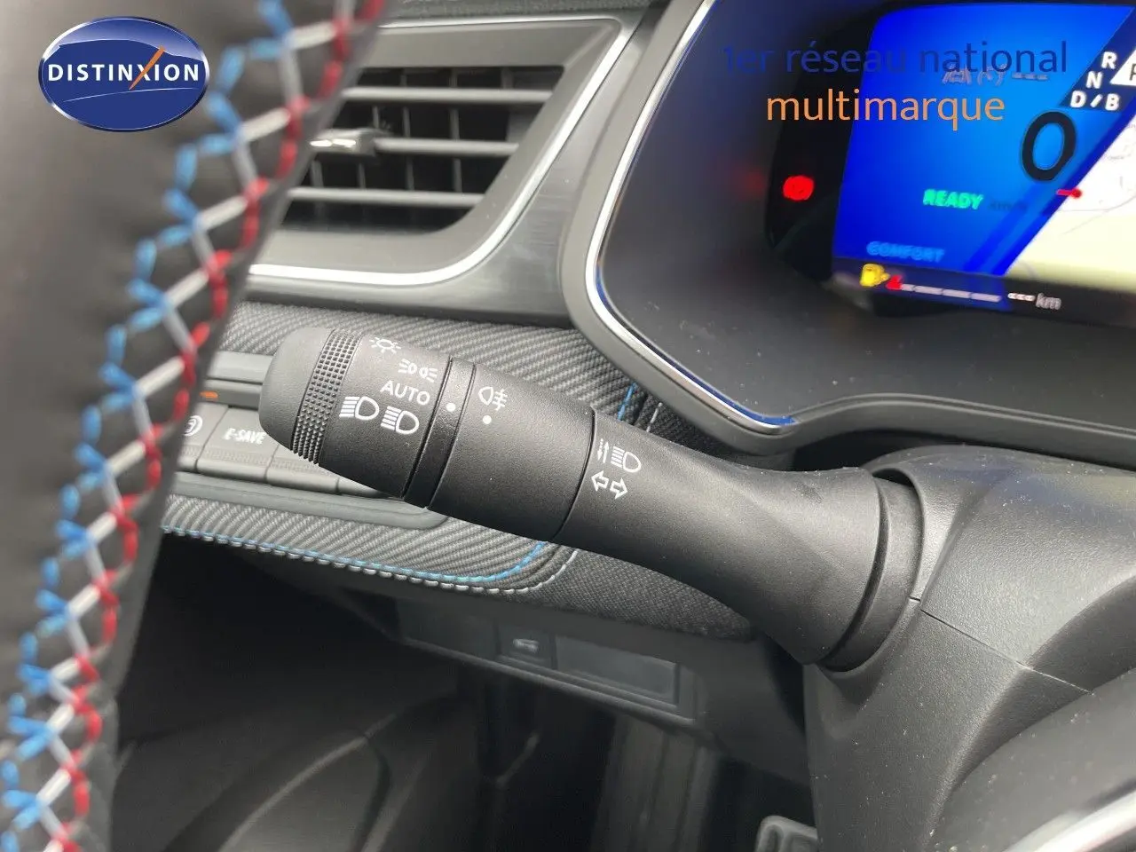 Gros plan sur la commande des phares à gauche du volant d’un Renault Symbioz gris Cassiopée, tableau de bord numérique visible.