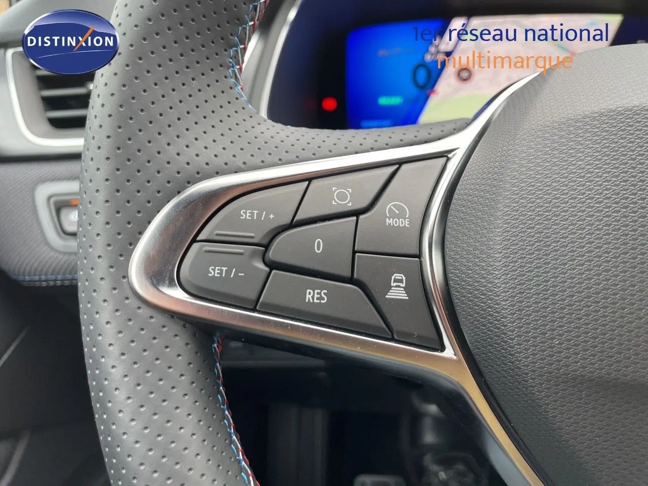 Gros plan sur les commandes à gauche du volant perforé avec surpiqûres bleues de la Renault Symbioz gris cassiopée.