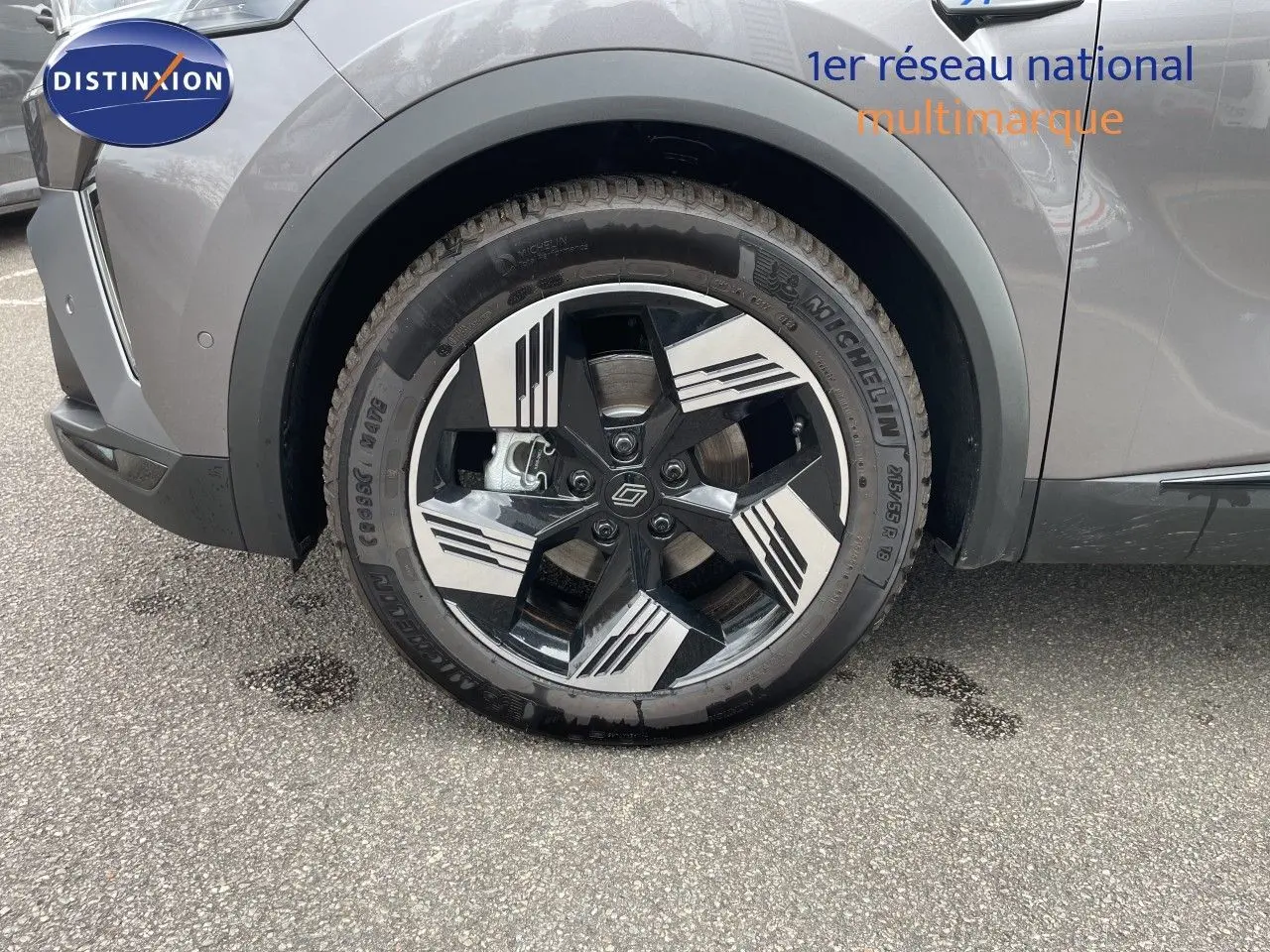 Gros plan sur la roue avant droite d'une Renault Symbioz gris cassiopée métal avec jante noire et argentée au design géométrique.
