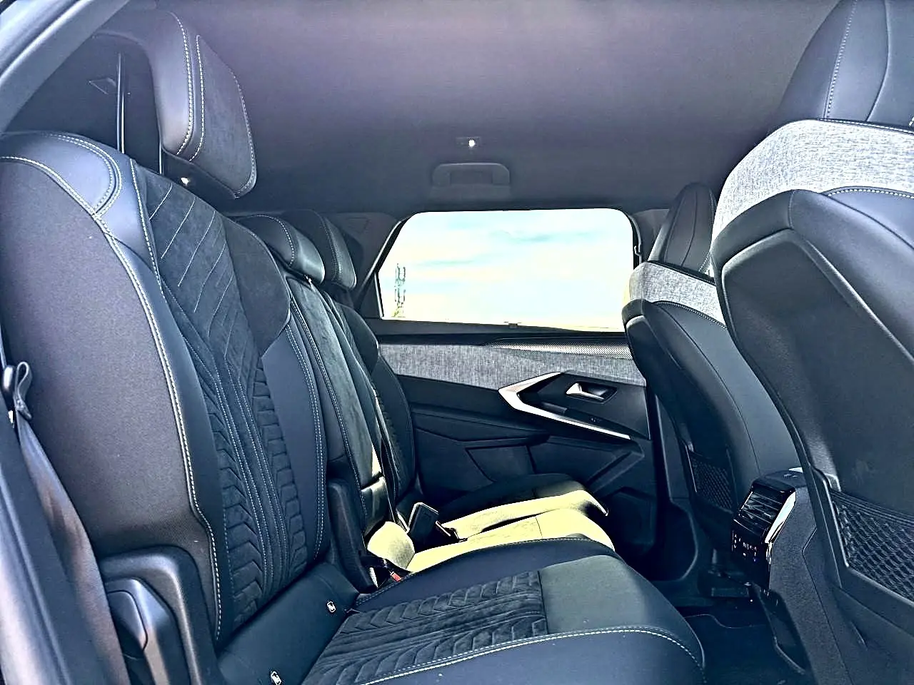 Vue latérale intérieure du rang 2 du Peugeot 5008 Hybrid 145 GT noir, avec sièges en cuir et tissu noir et gris.