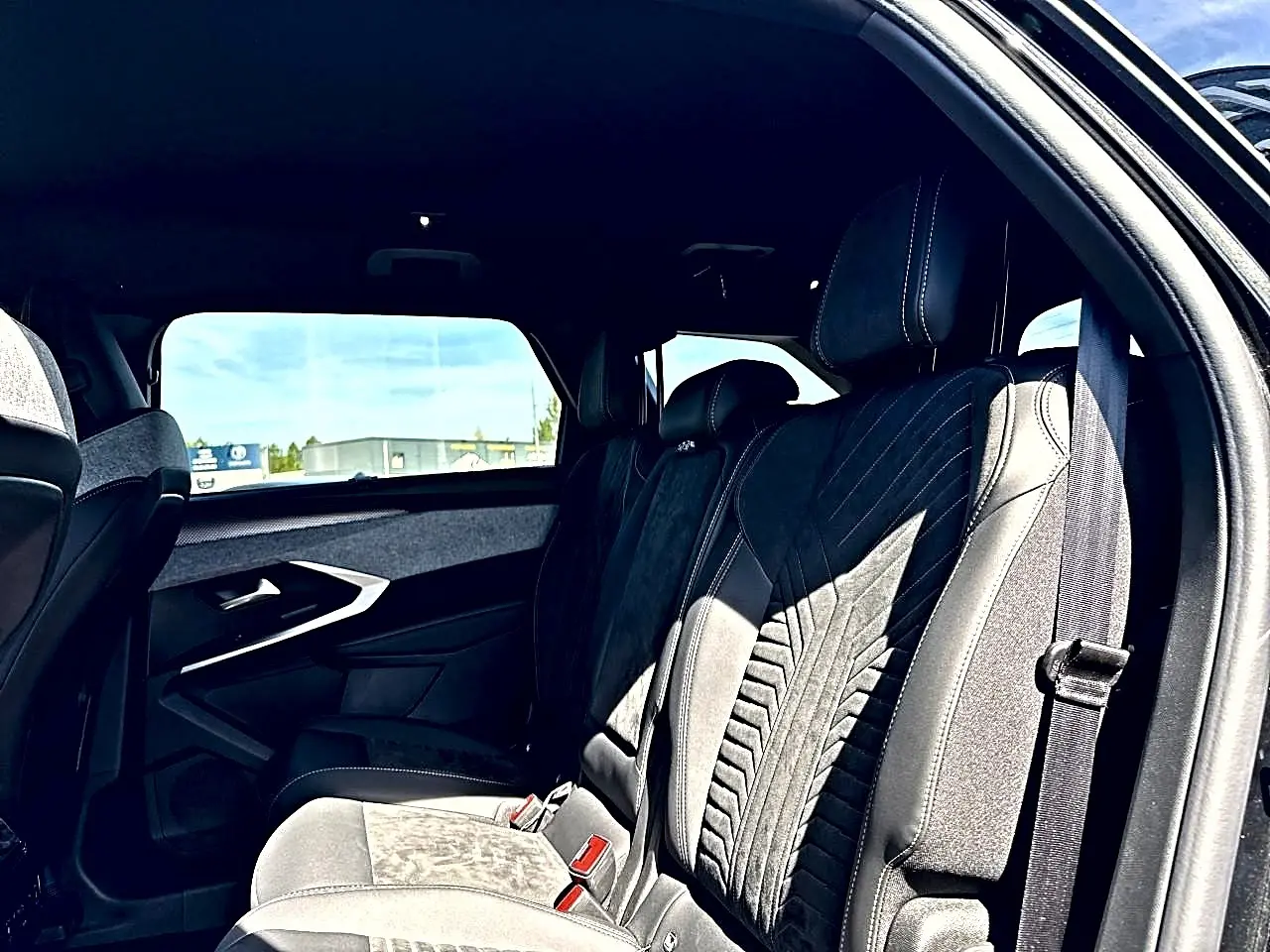Vue intérieure côté droit des sièges arrière en tissu et cuir du Peugeot 5008 Hybrid 145 GT noir, avec ceinture visible.