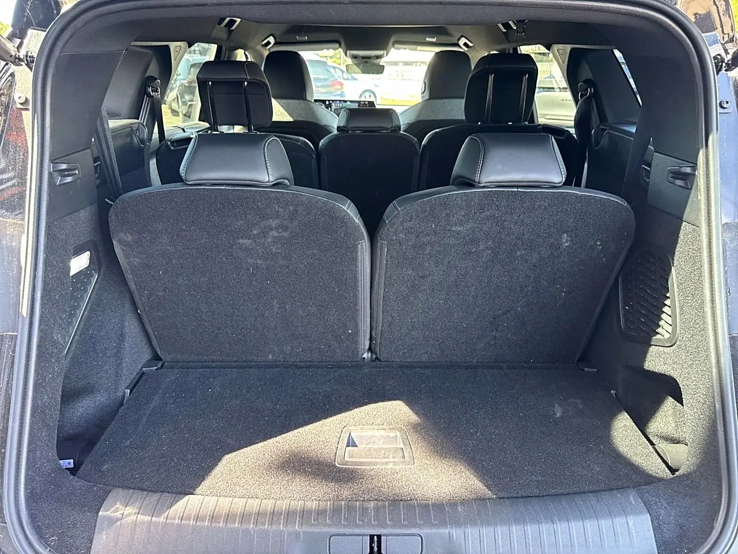 Vue arrière du coffre ouvert d’un Peugeot 5008 noir, montrant les sièges arrière relevés et l’habitacle intérieur.