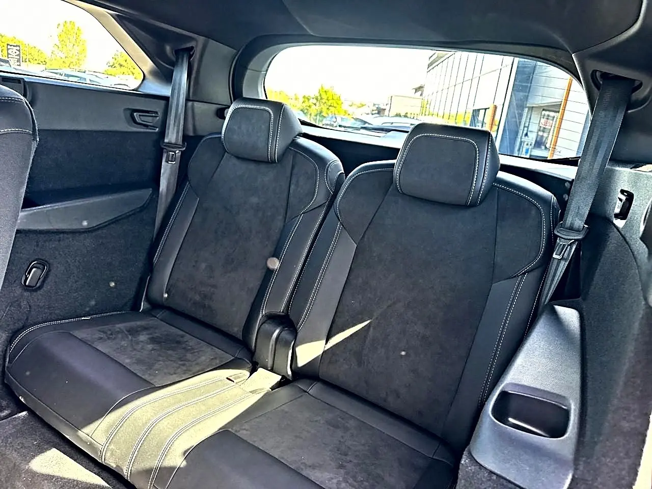 Vue intérieure arrière montrant les deux sièges supplémentaires noirs avec surpiqûres blanches du Peugeot 5008 Hybrid 145 GT 2025.