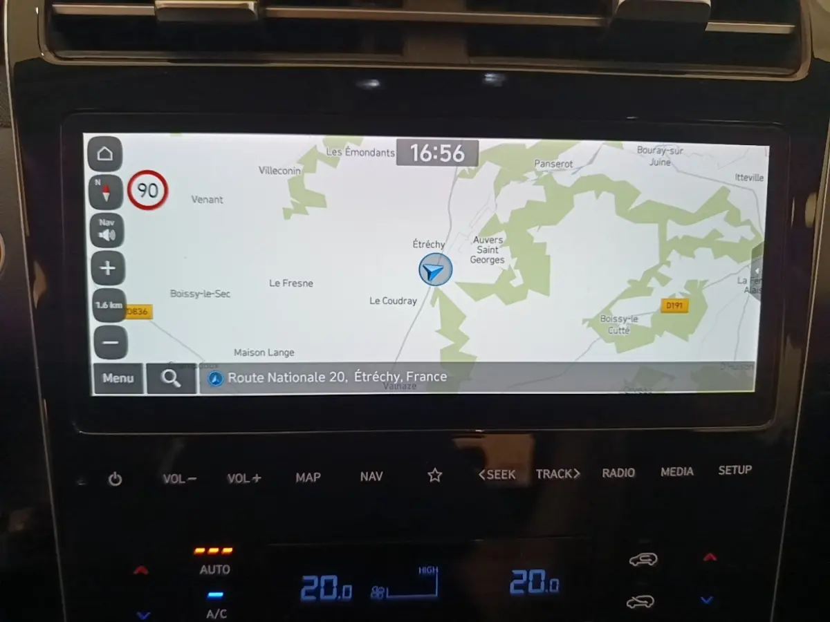 Écran tactile central du Hyundai Tucson bleu 2021 affichant la navigation GPS avec carte et commandes climatisation digitales.