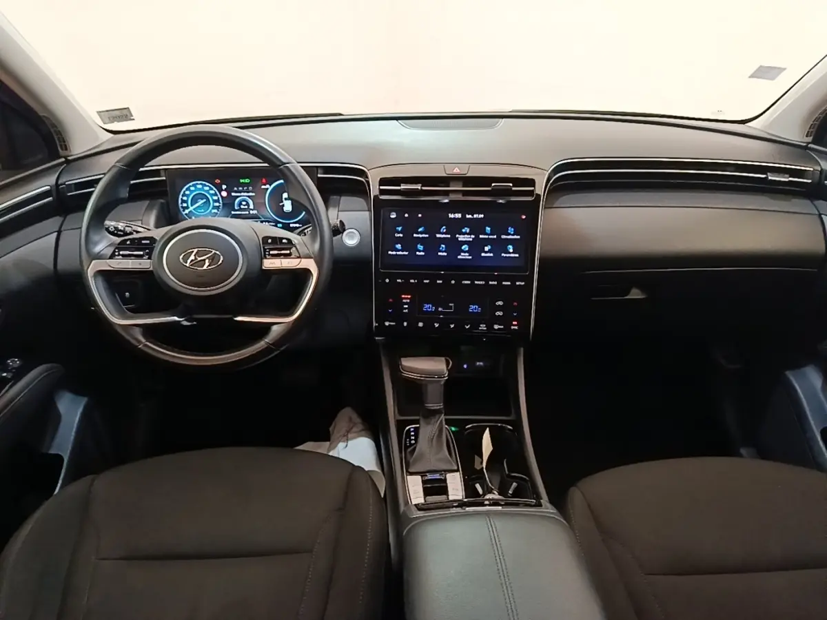 Vue intérieure avant du Hyundai Tucson 2021, tableau de bord noir avec écran tactile central et volant multifonctions.