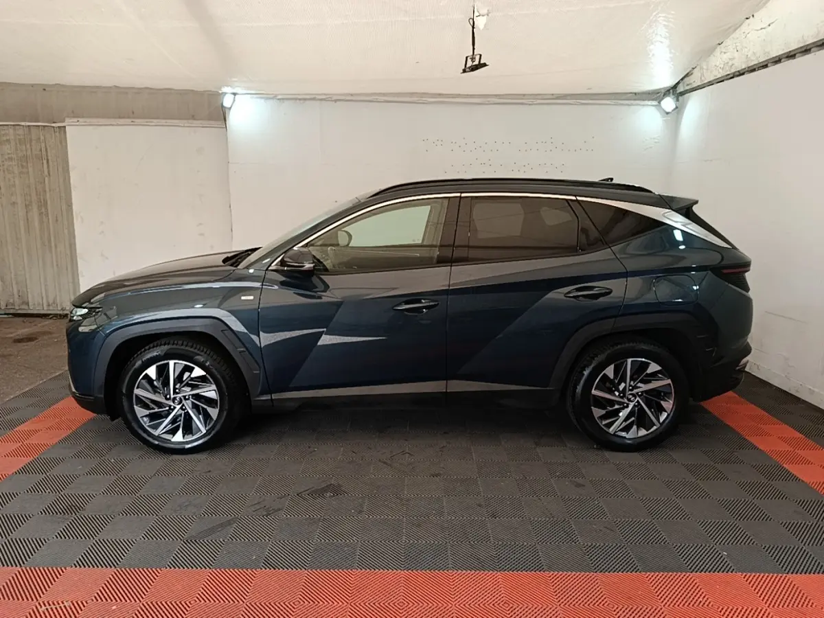 Vue de profil côté gauche du Hyundai Tucson bleu 2021 avec jantes alliage et vitres teintées dans un garage.