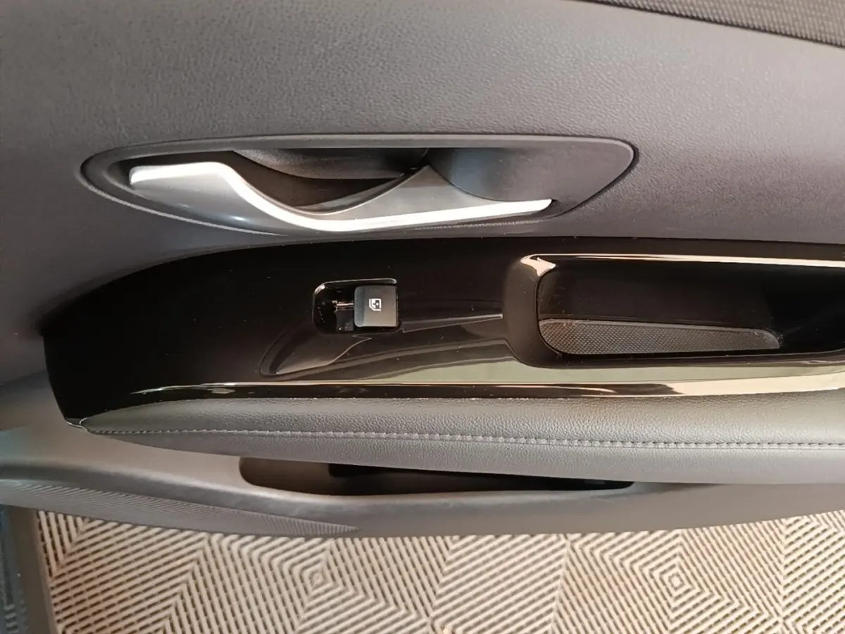 Gros plan sur la poignée intérieure et le bouton de verrouillage de la porte côté conducteur du Hyundai Tucson bleu 2021.