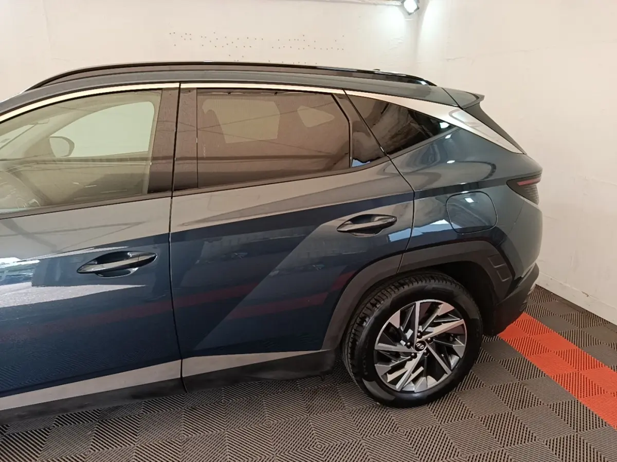 Vue latérale droite du Hyundai Tucson bleu avec jante alliage et toit noir dans un garage fermé.
