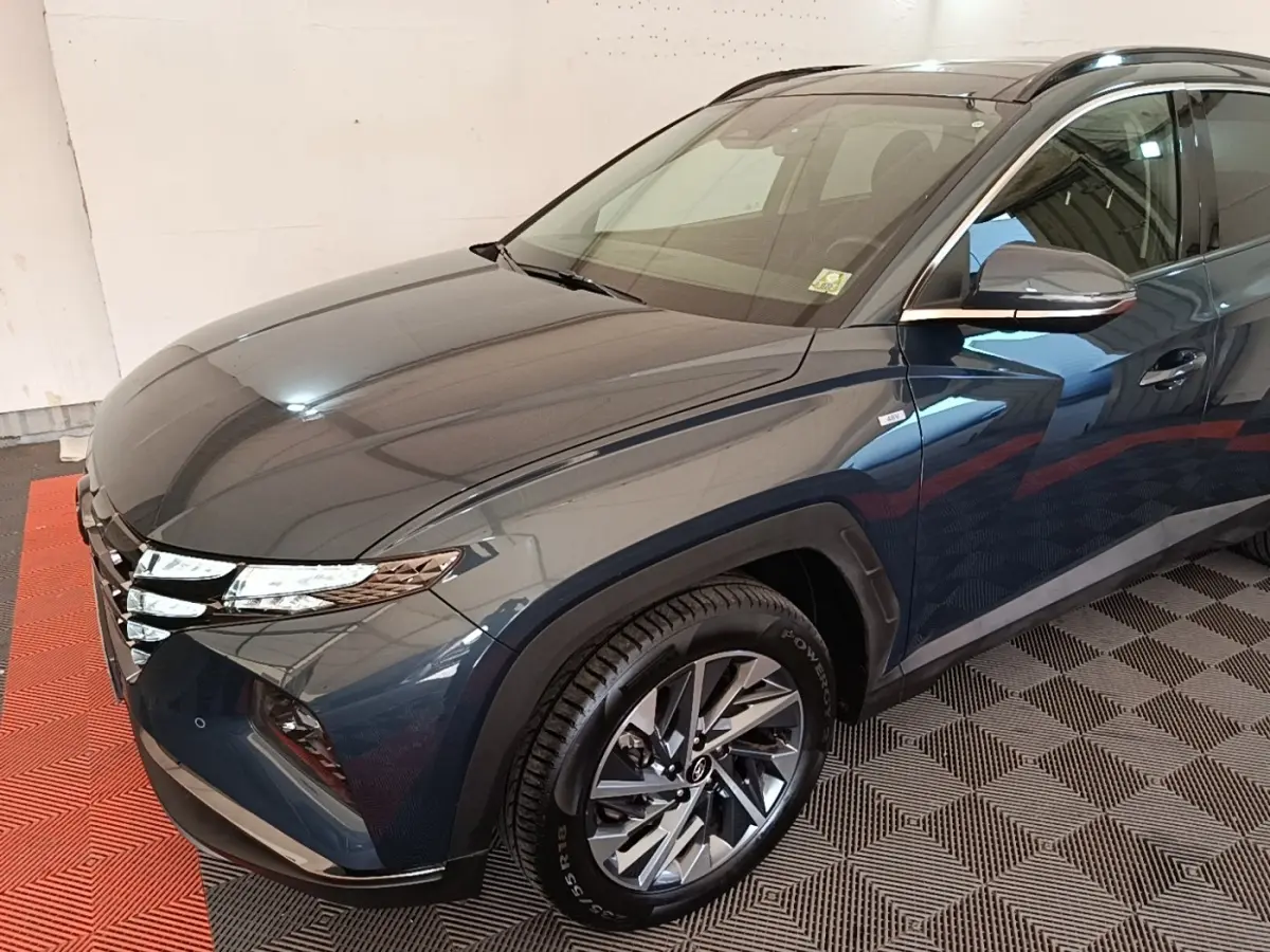 Vue 3/4 avant droit du Hyundai Tucson bleu avec jantes alliage et phares LED distinctifs.