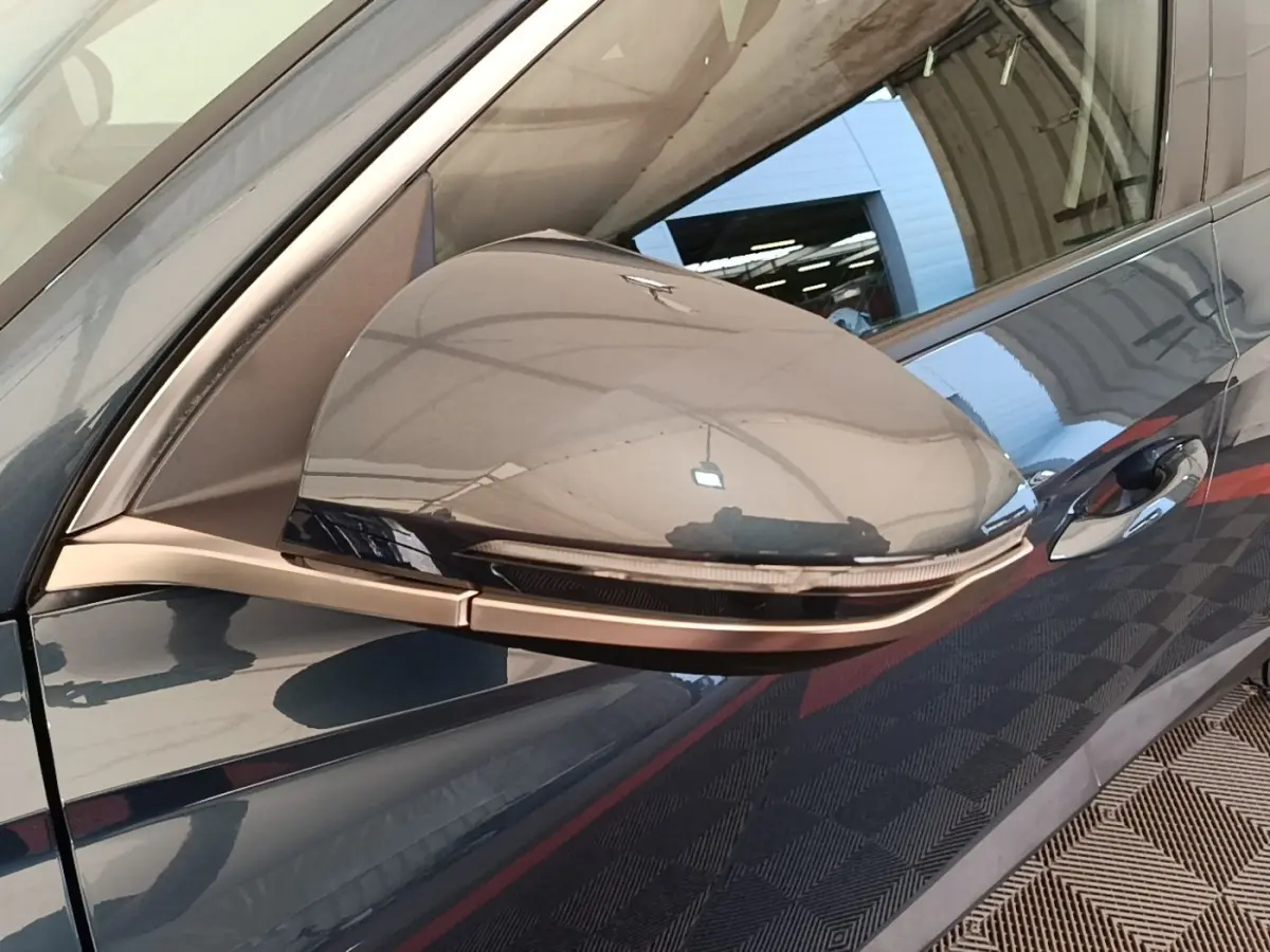 Rétroviseur côté conducteur bleu du Hyundai Tucson 2021 avec clignotant intégré et poignée de porte visible.