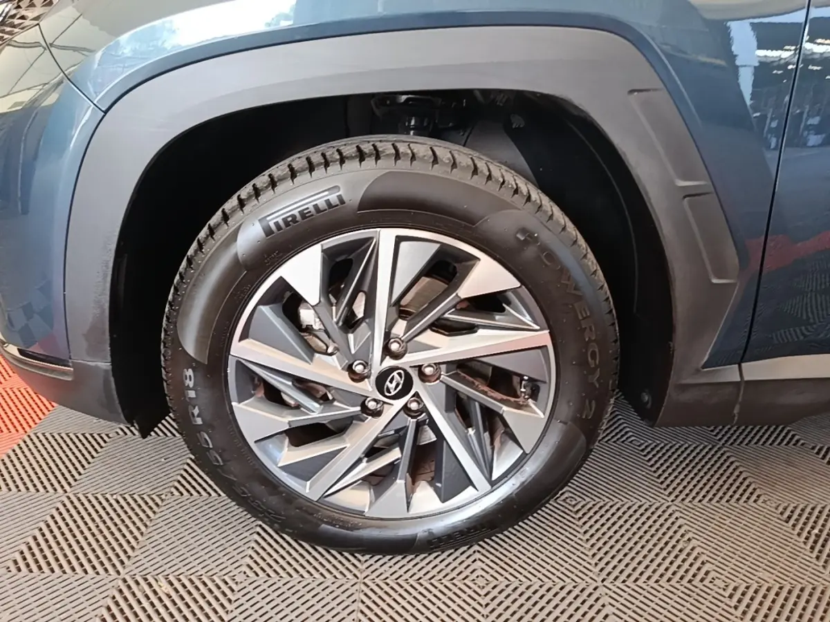 Gros plan sur la roue avant gauche du Hyundai Tucson bleu, avec jante alliage et pneu Pirelli visible.