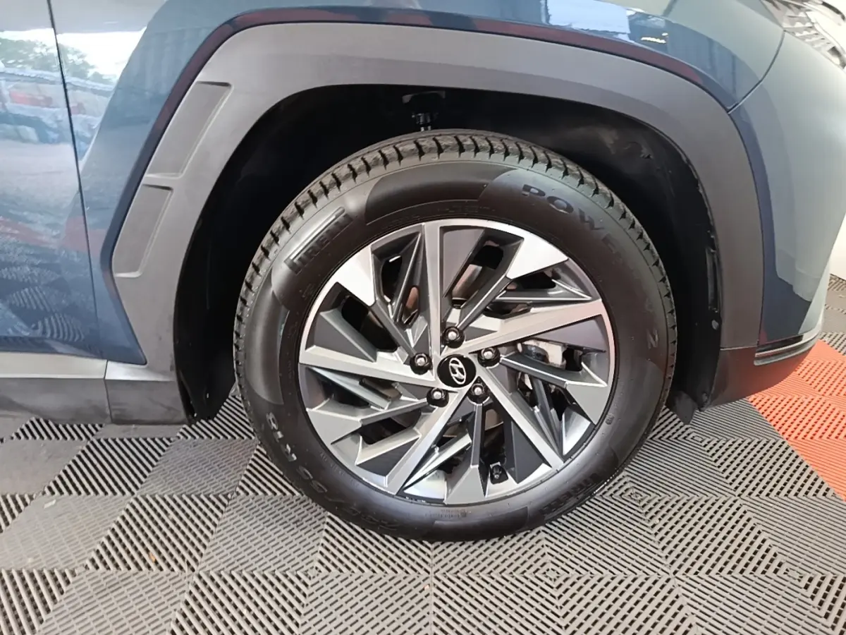 Gros plan sur la roue avant gauche bleu métallisé du Hyundai Tucson 2021 avec jante alliage au design moderne.