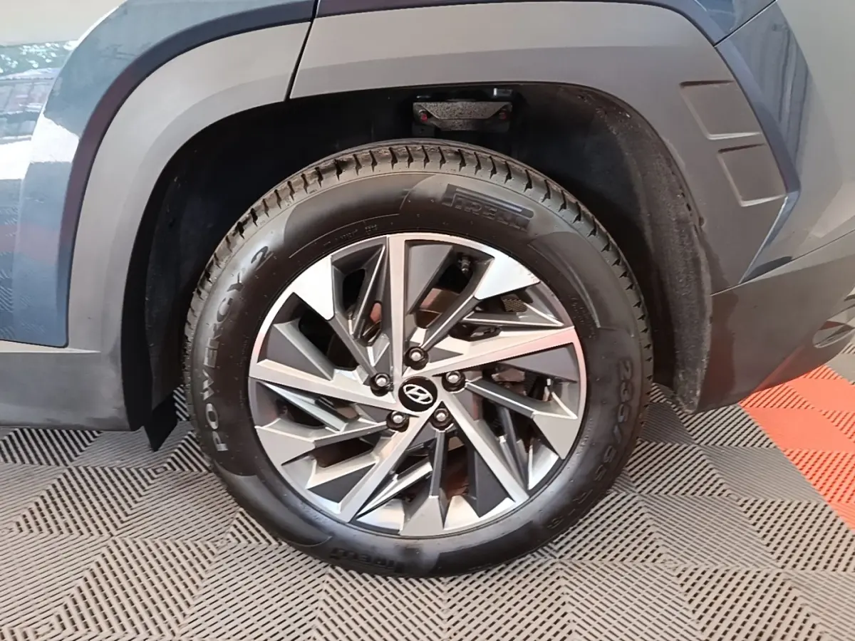 Gros plan sur la roue avant droite d’un Hyundai Tucson bleu avec jante alliage moderne et pneu Pirelli.