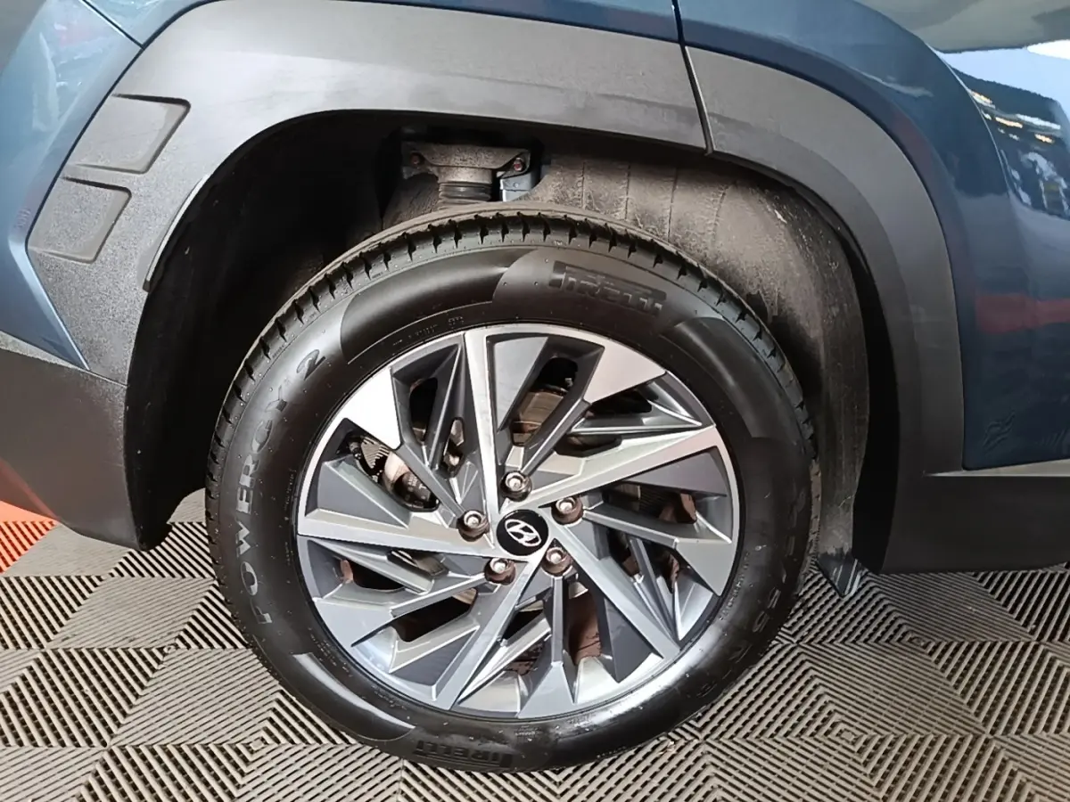 Gros plan sur la roue avant gauche d’un Hyundai Tucson bleu, avec jante alliage et pneu Pirelli Powergy.