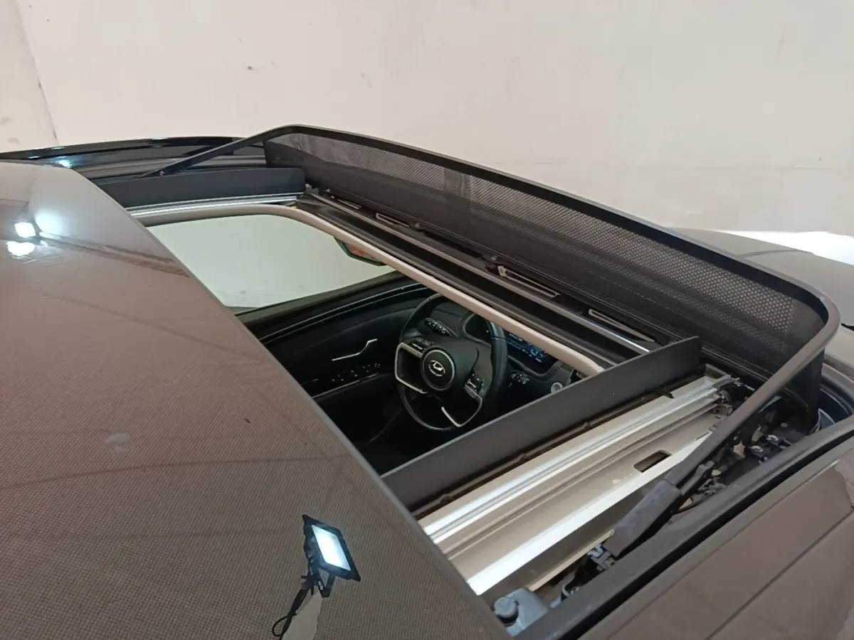 Vue plongeante sur l'intérieur d'un Hyundai Tucson bleu avec toit ouvrant panoramique ouvert.