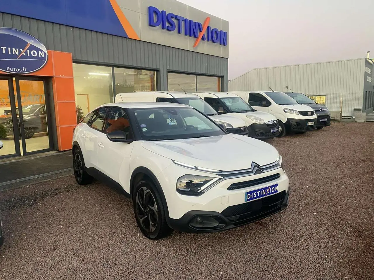 Citroën C4 blanc vue 3/4 avant droit, toit noir et jantes noires, devant concession Distinxion.