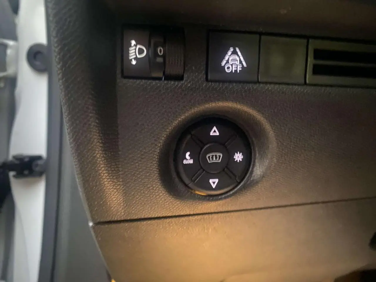 Gros plan sur les commandes d'éclairage et d'aide à la conduite du tableau de bord d'une Citroën C4 blanche de 2021.