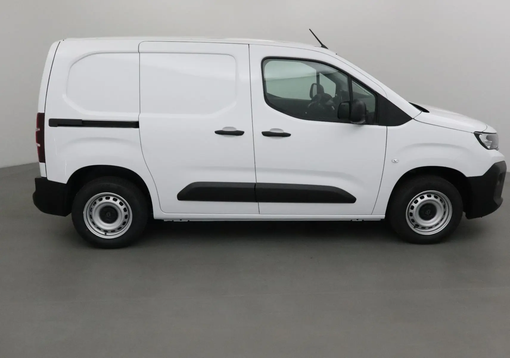 Vue de profil côté droit d’un utilitaire blanc Peugeot Partner 2025 avec portes coulissantes et protections noires.