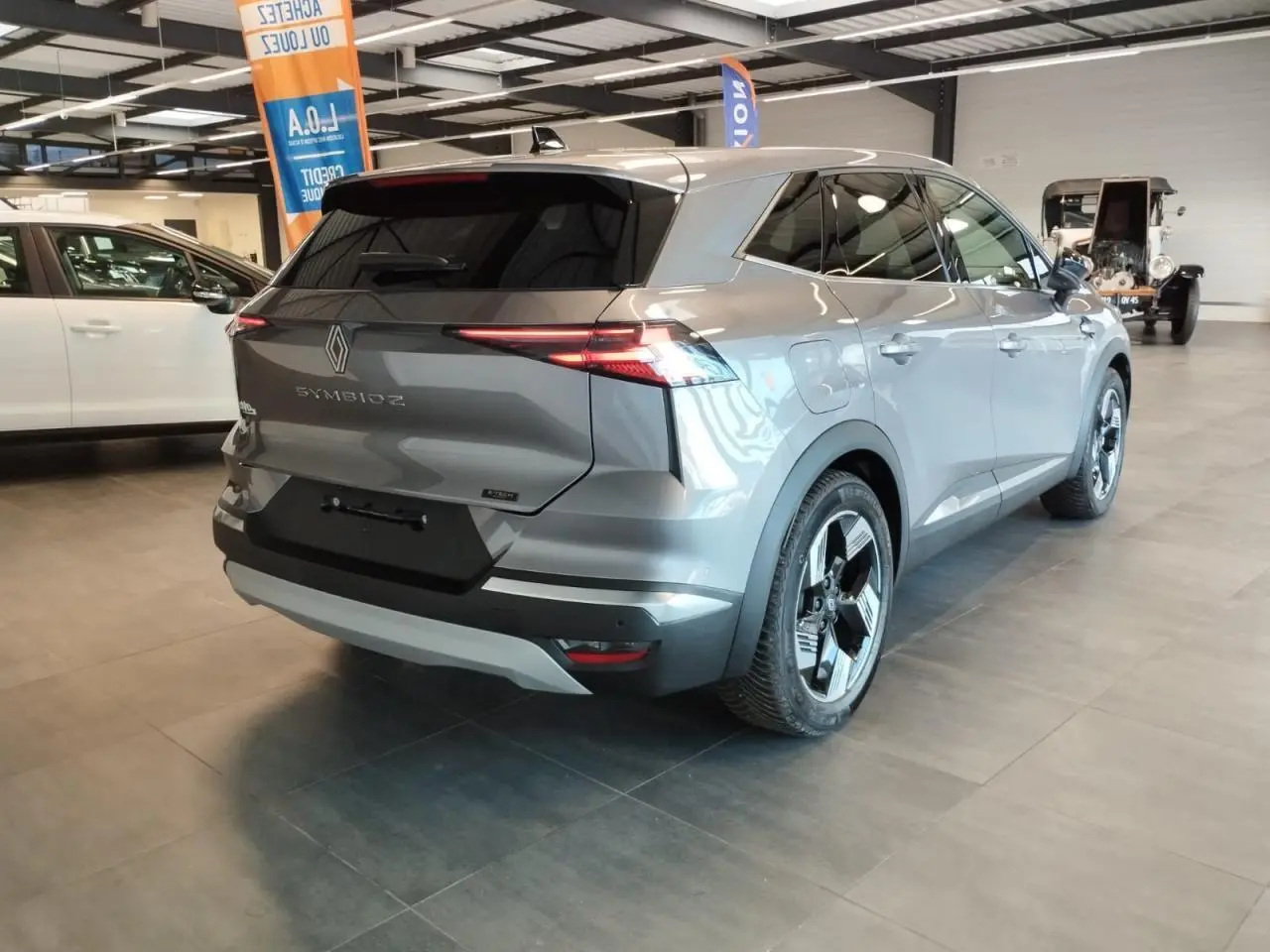 Vue 3/4 arrière droite du Renault SYMBIOZ gris Cassiopée avec jantes 18 pouces Gravity en showroom.