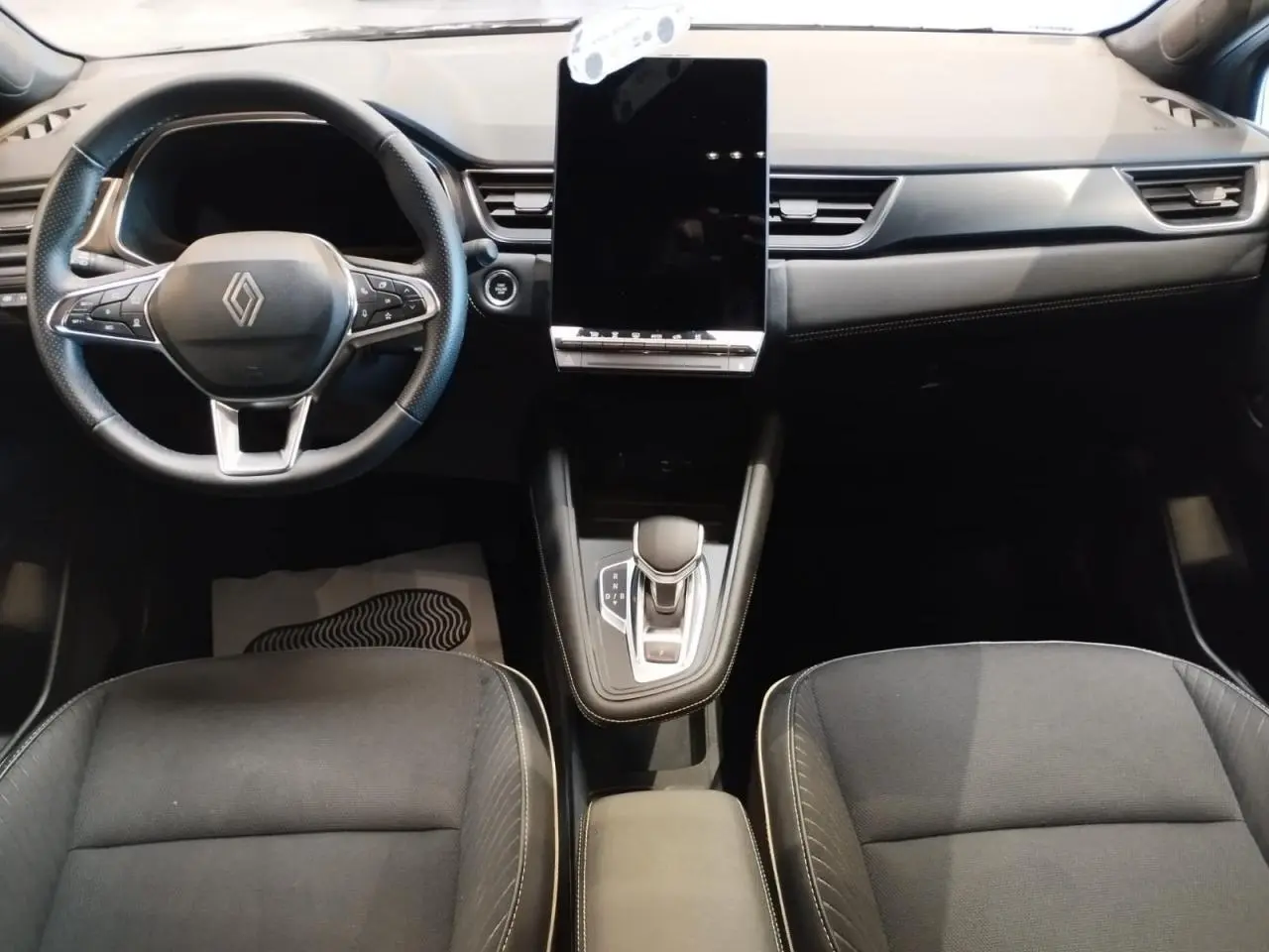 Vue intérieure avant du Renault Symbioz 2025 avec tableau de bord noir et écran tactile vertical central.