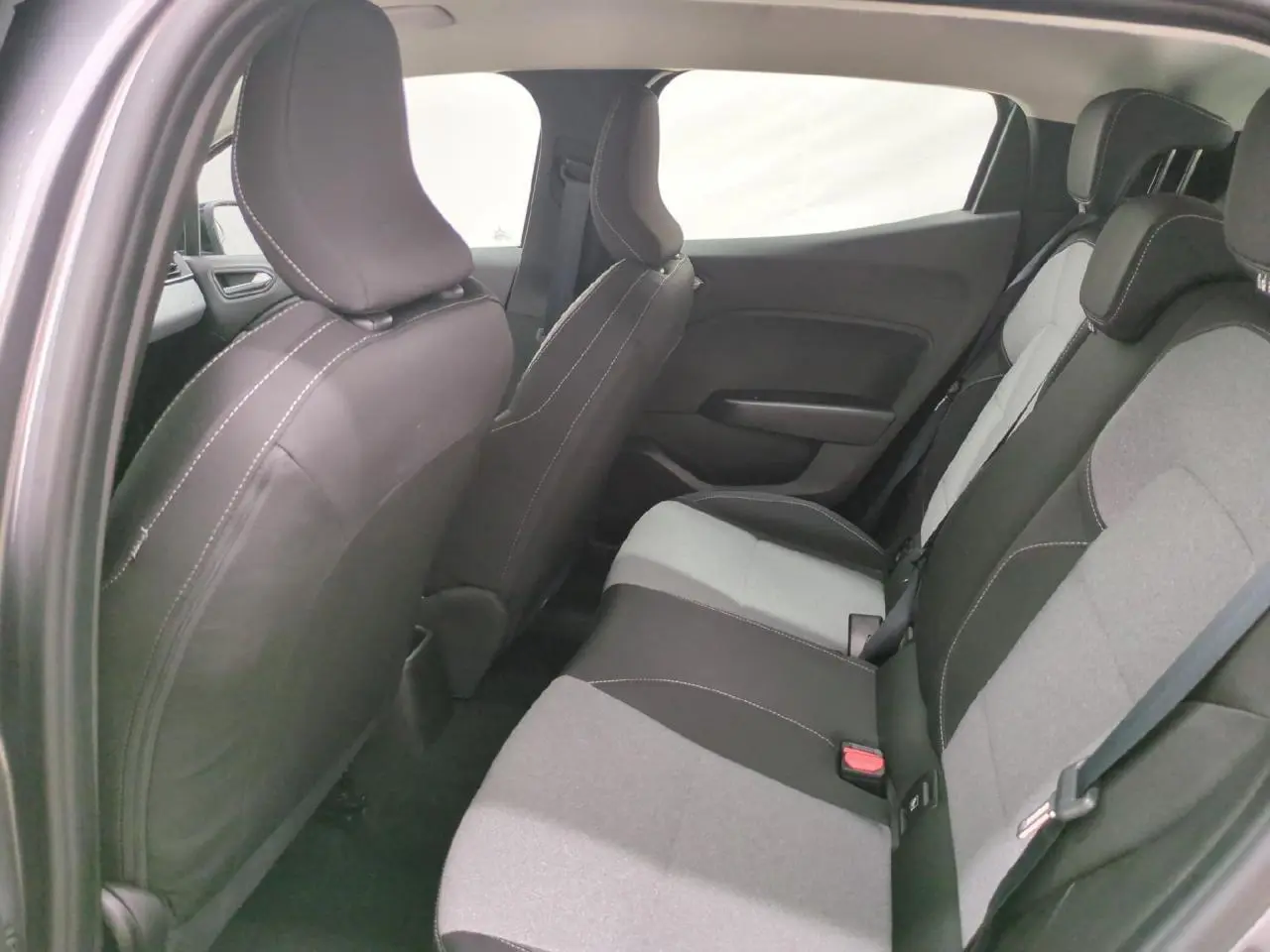 Vue intérieure côté gauche des sièges arrière gris et noirs de la Renault Clio 1.0 Tce 90 2024 avec appuis-têtes réglables.