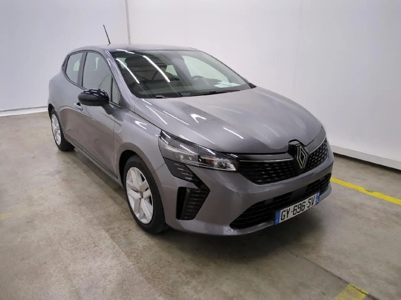 Renault Clio 2024 gris foncé vue 3/4 avant avec calandre noire et jantes alliage argentées.