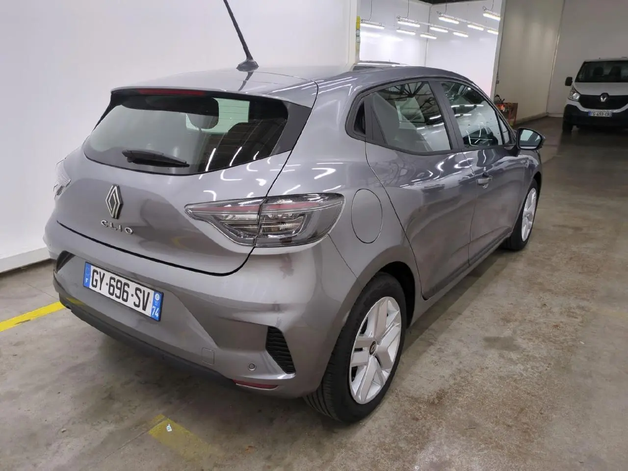 Vue 3/4 arrière droite d'une Renault Clio 2024 gris foncé avec feux arrière LED et jantes alliage.