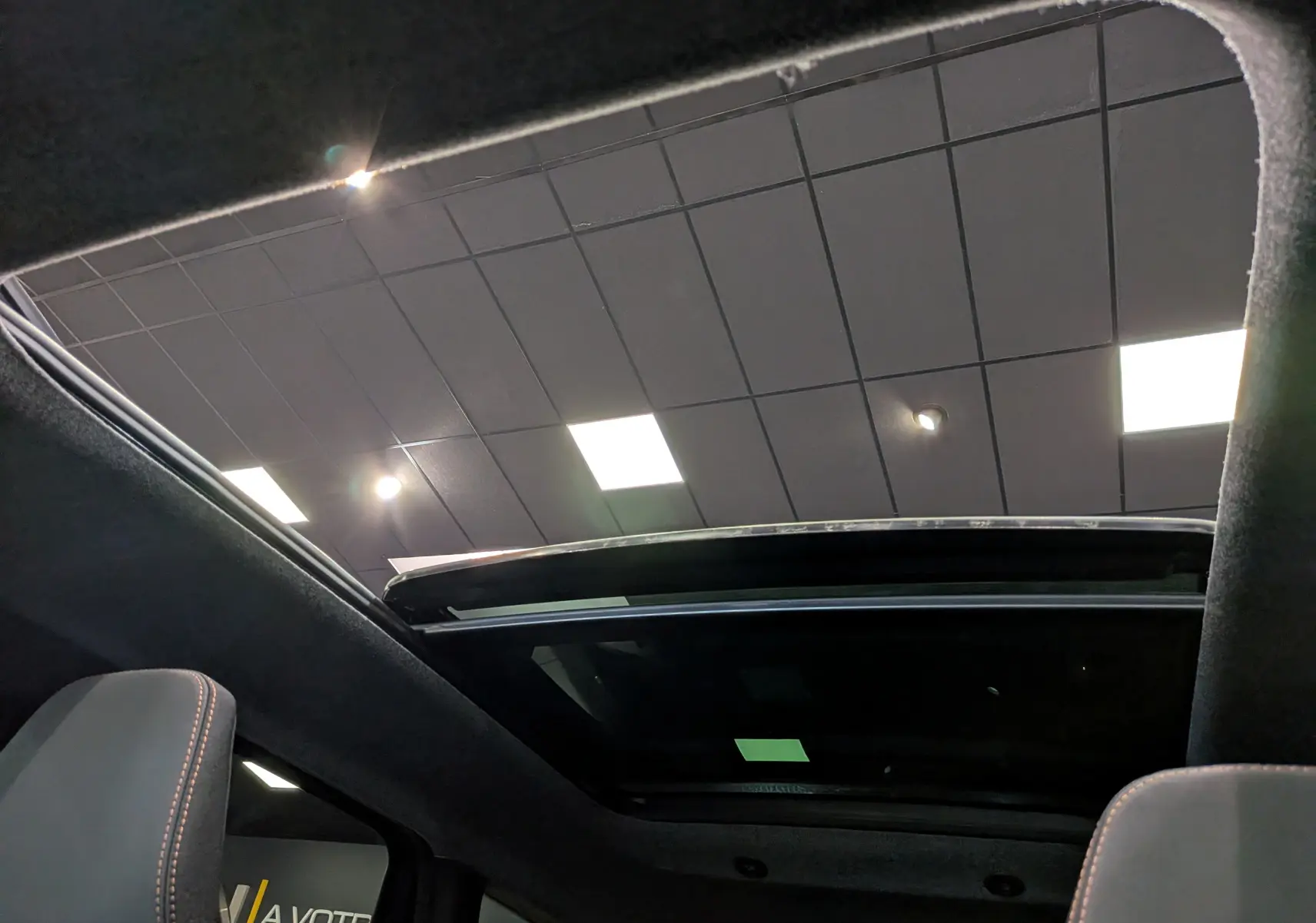 Toit ouvrant panoramique vu de l'intérieur du Dacia Bigster 2026, avec ciel de toit noir et sièges tissu gris.