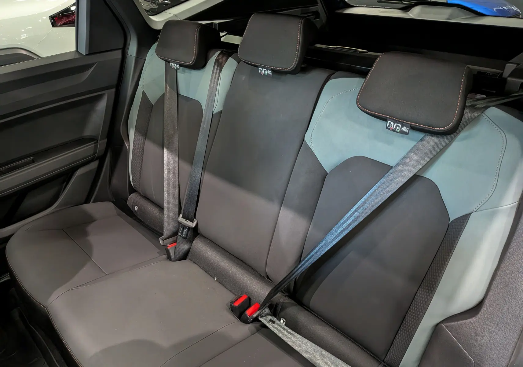 Vue intérieure sur la banquette arrière bicolore noire et bleu indigo du Dacia Bigster 2026 avec ceintures de sécurité.