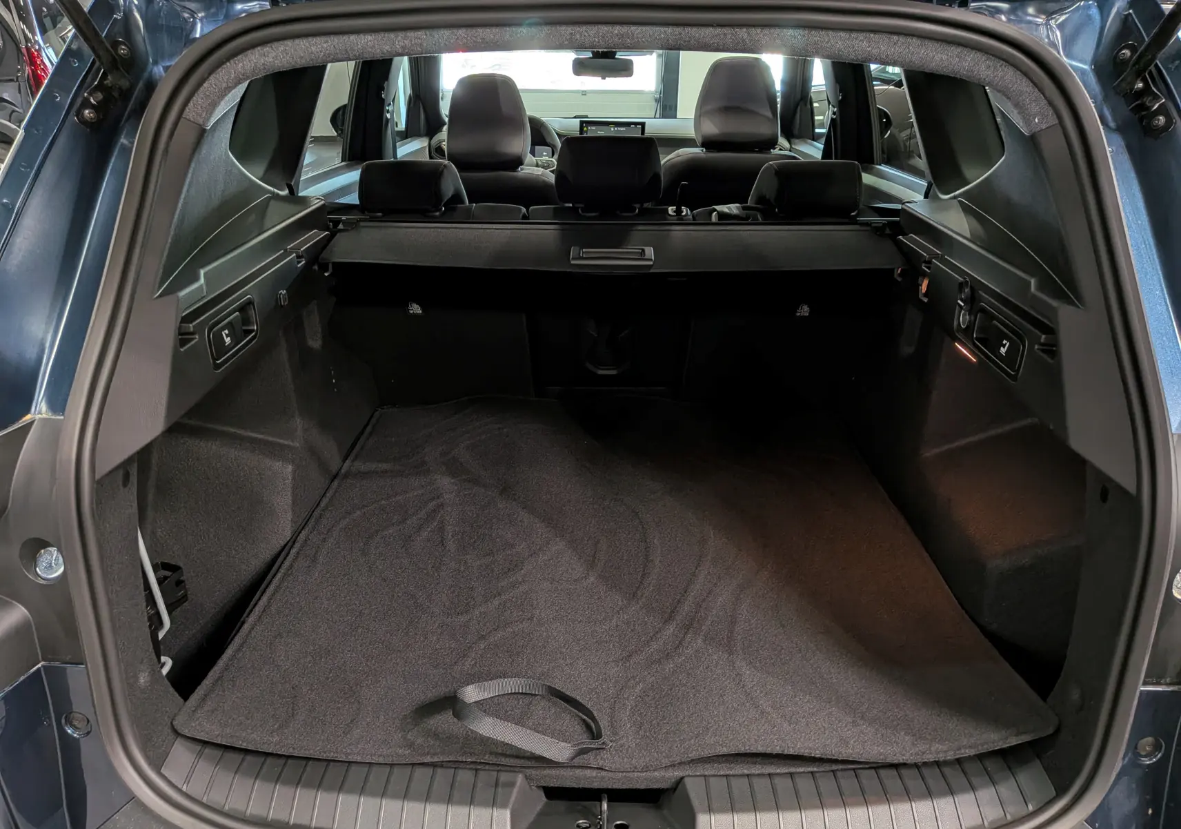 Vue arrière du coffre spacieux du Dacia Bigster Bleu Indigo, avec banquette arrière et cache-bagages visibles.