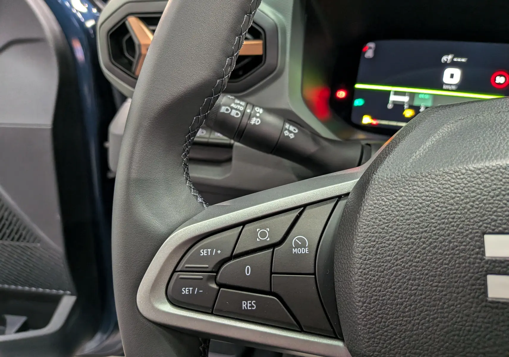 Gros plan sur la partie gauche du volant noir du Dacia Bigster 2026, avec commandes de régulateur et tableau de bord numérique.
