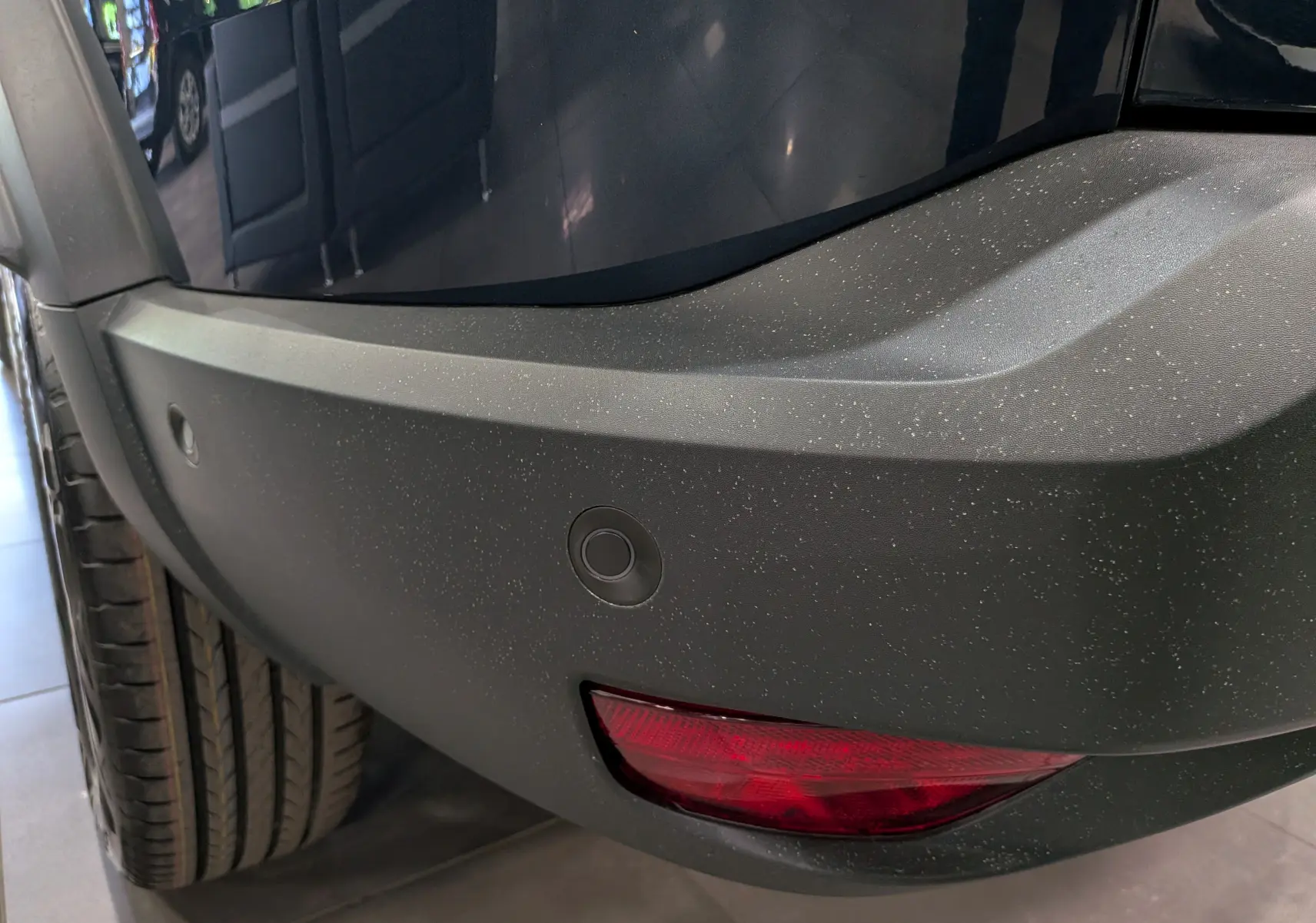 Gros plan sur le pare-chocs arrière droit bleu indigo du Dacia Bigster avec feu antibrouillard et capteurs de stationnement.