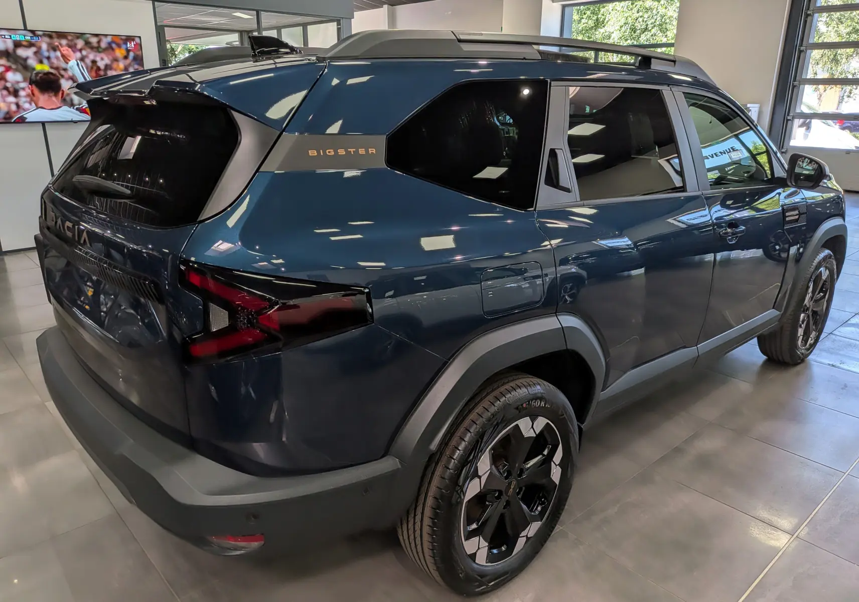 Vue 3/4 arrière droite du Dacia Bigster bleu indigo avec jantes noires et logo Bigster sur la custode.