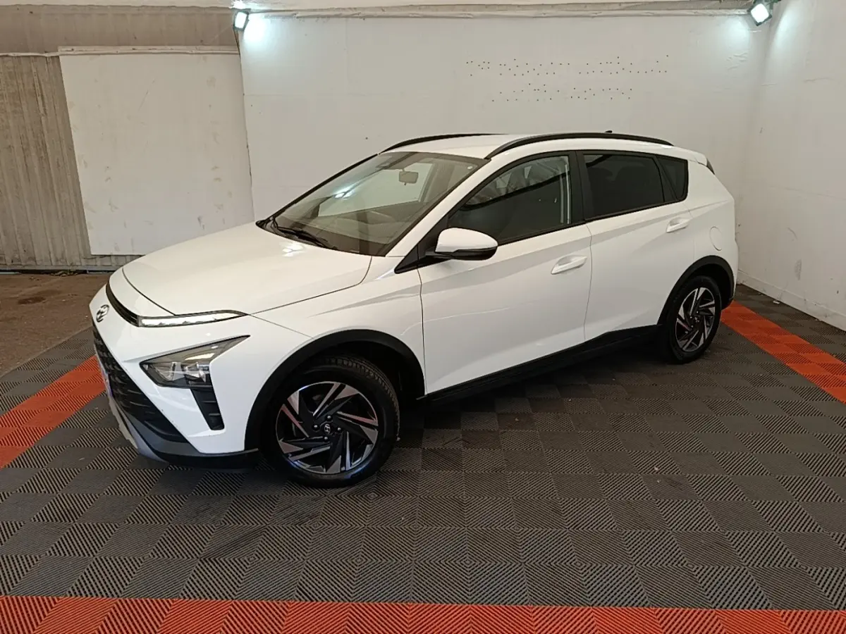 Hyundai Bayon blanc en 3/4 avant droit, avec jantes noires et toit ouvrant visible en intérieur fermé.