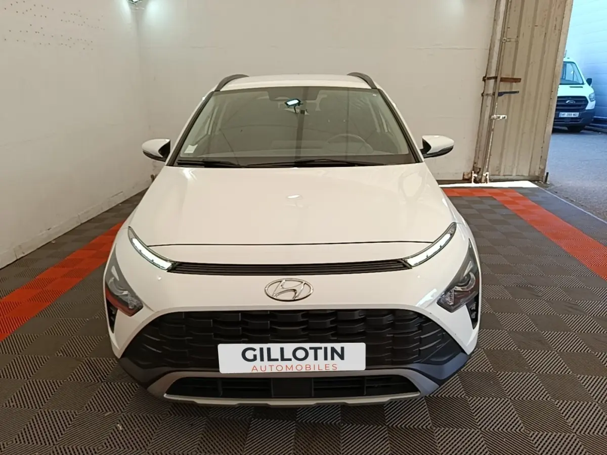 Vue avant d'un Hyundai Bayon blanc avec calandre noire et feux LED fins dans un garage.