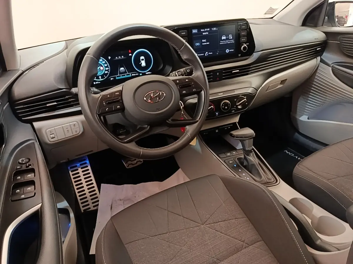 Vue intérieure avant du Hyundai Bayon blanc 2024, volant cuir multifonctions et écran tactile central visible.