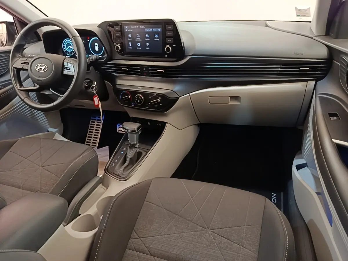 Vue intérieure avant droite du Hyundai Bayon 2024 avec tableau de bord noir et gris, écran tactile central et volant multifonctions.