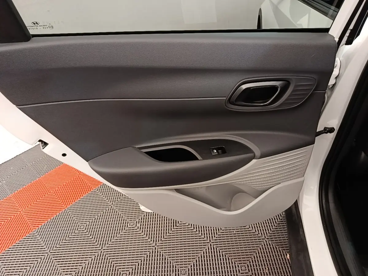 Vue intérieure de la porte arrière droite blanche du Hyundai Bayon 2024 avec garniture bicolore noire et grise.