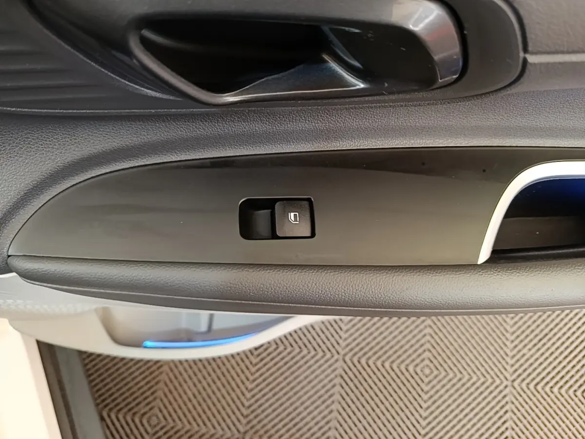 Gros plan sur la commande de lève-vitre côté conducteur de la Hyundai Bayon blanche, intérieur noir.