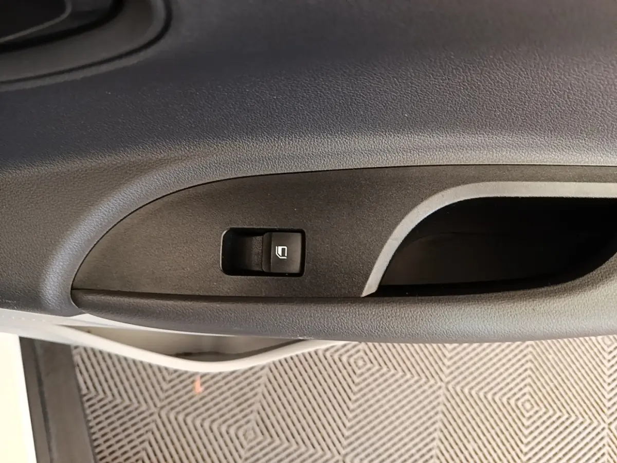 Gros plan sur la commande de lève-vitre côté conducteur d’une Hyundai Bayon blanche, intérieur noir.