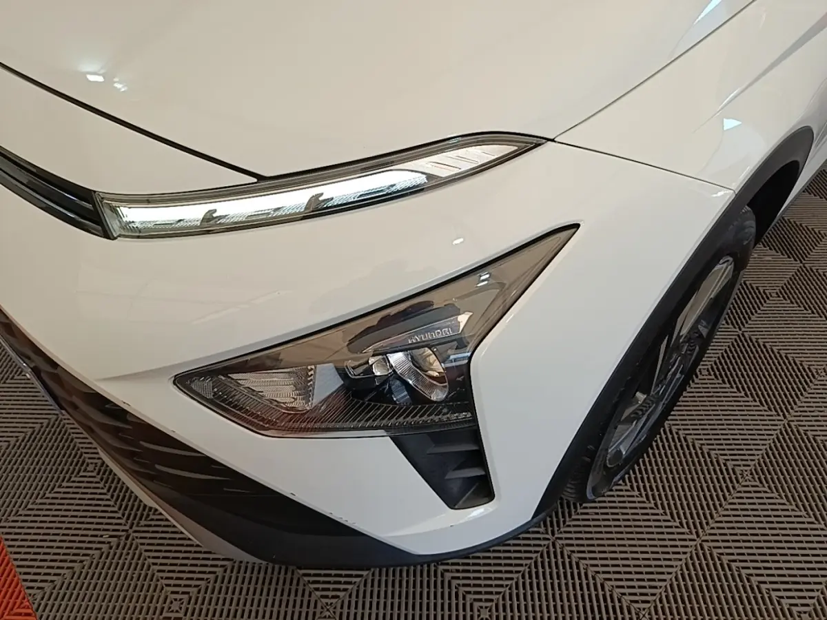 Gros plan sur l'avant droit blanc du Hyundai Bayon 2024, mettant en valeur les phares LED et la calandre noire.