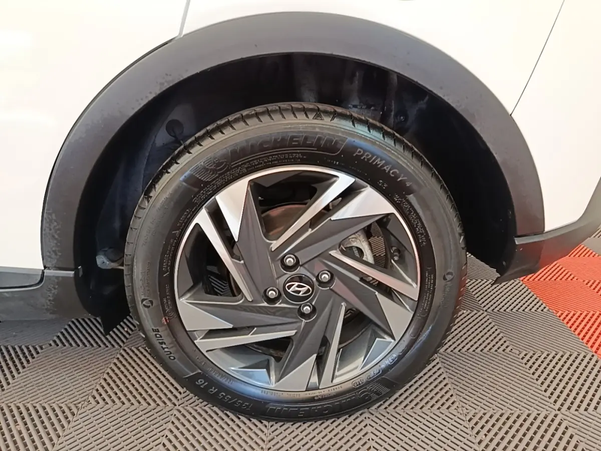 Gros plan sur la roue avant droite d'une Hyundai Bayon blanche, avec jante alliage au design géométrique bicolore.